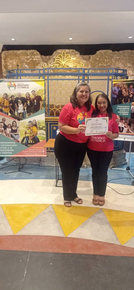 man wearing a black jacket, white shirt, blue jeans, and brown boots, playing a white electric guitar while sitting on an amp